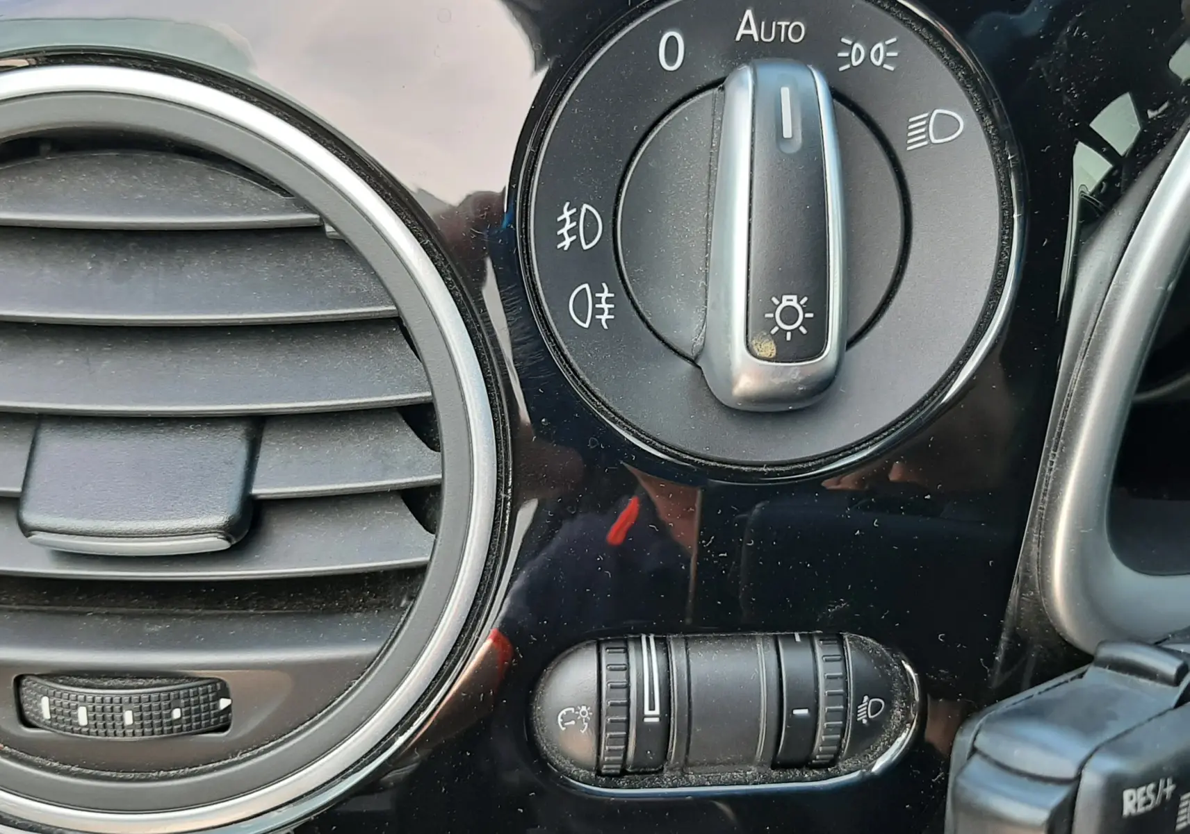 Détail du tableau de bord noir du Volkswagen New Beetle 2015 montrant la commande des phares et la sortie d’air circulaire.