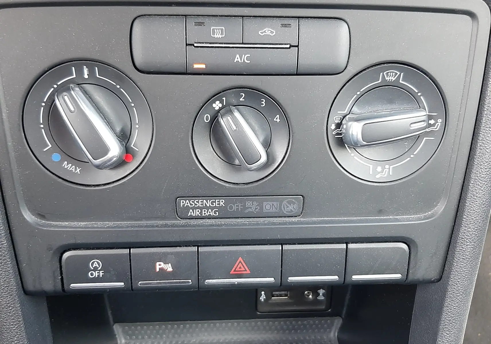 Gros plan sur la console centrale noire du Volkswagen New Beetle 2015, avec commandes de climatisation et boutons fonctionnels.