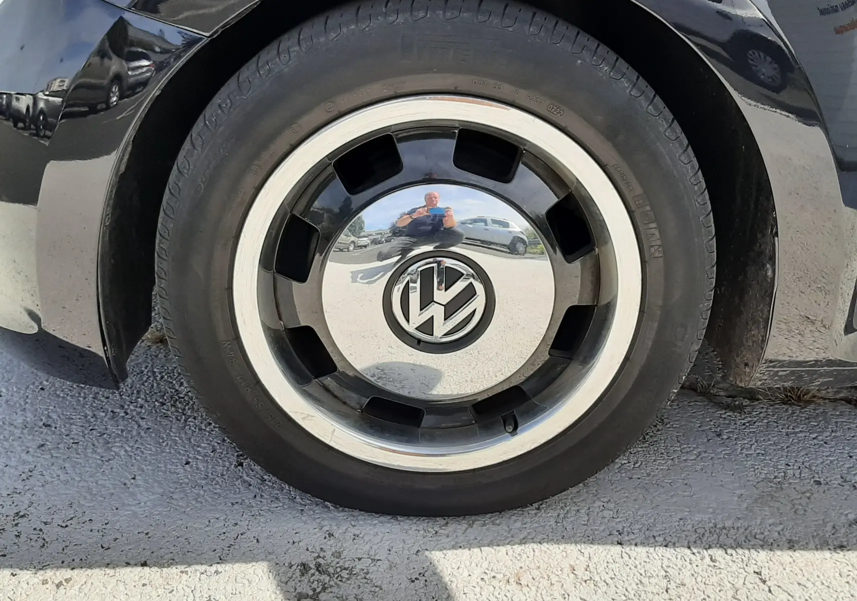 Gros plan sur la roue avant droite noire d’un Volkswagen New Beetle 2015 avec jante chromée et logo VW central.
