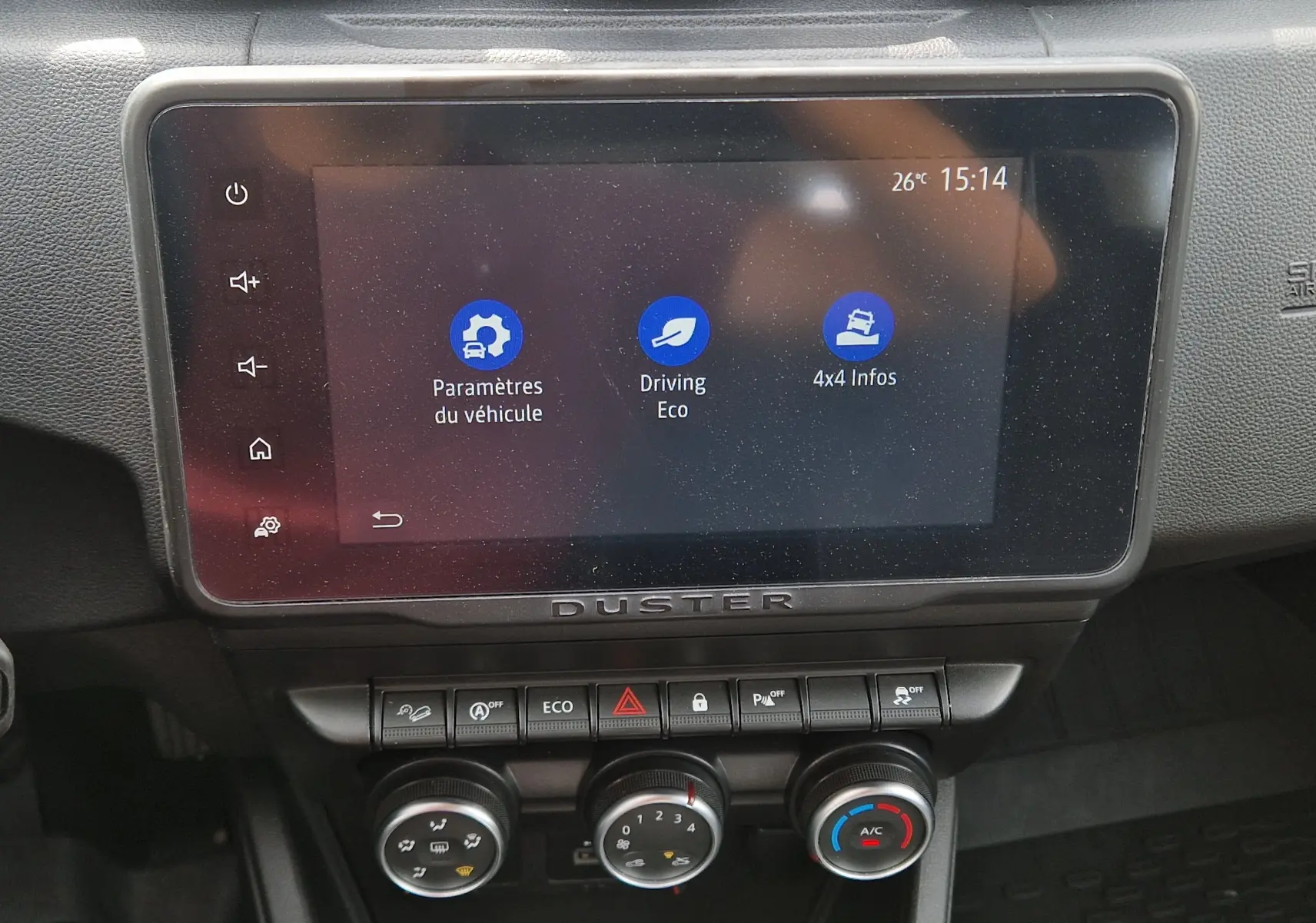 Vue rapprochée de l'écran tactile central et des commandes de climatisation du Dacia Duster 2023, intérieur noir.