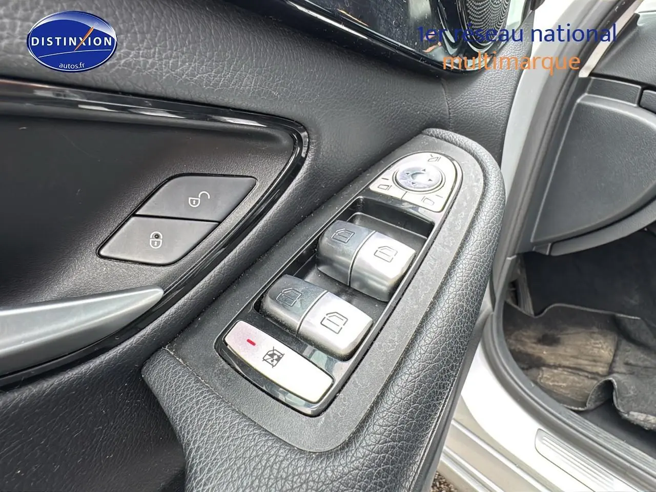Gros plan sur les commandes de lève-vitres côté conducteur d'une Mercedes Classe C 180 d business gris alu de 2017.