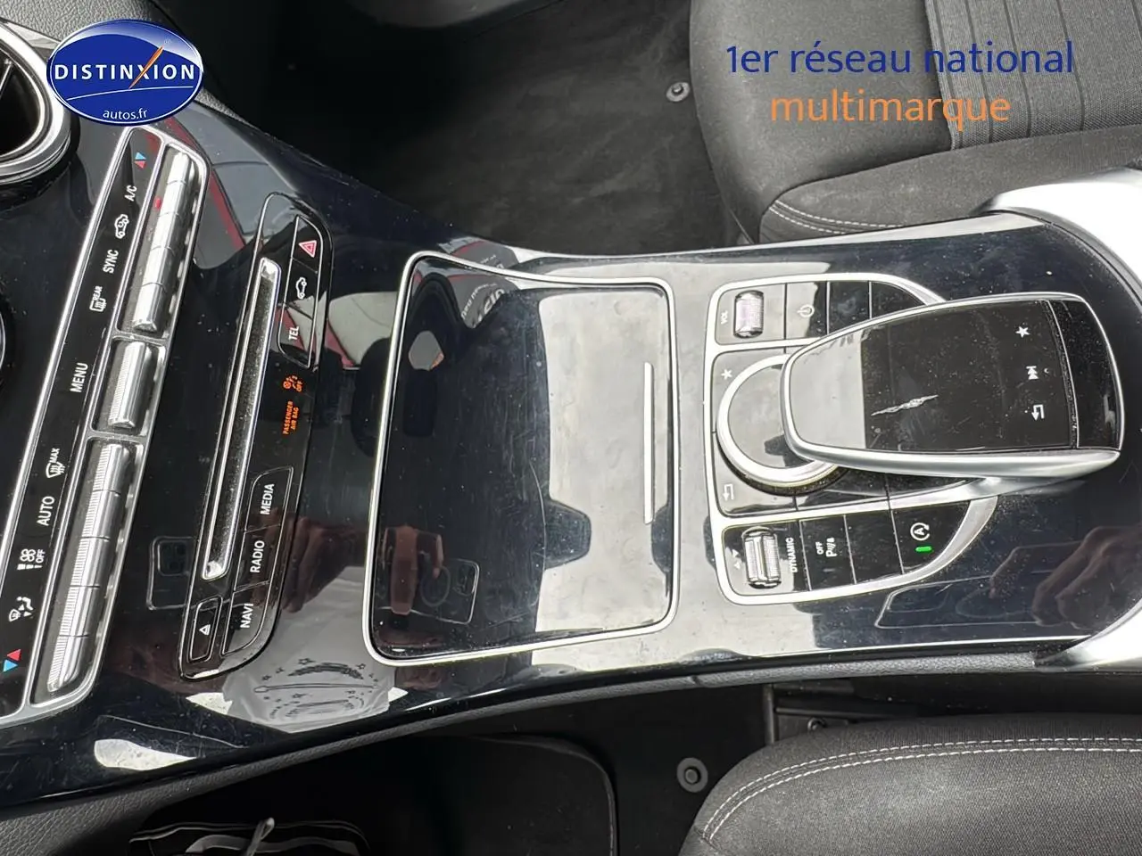 Vue rapprochée de la console centrale noire brillante de la Mercedes Classe C 180 d business 2017 avec commandes multimédia.