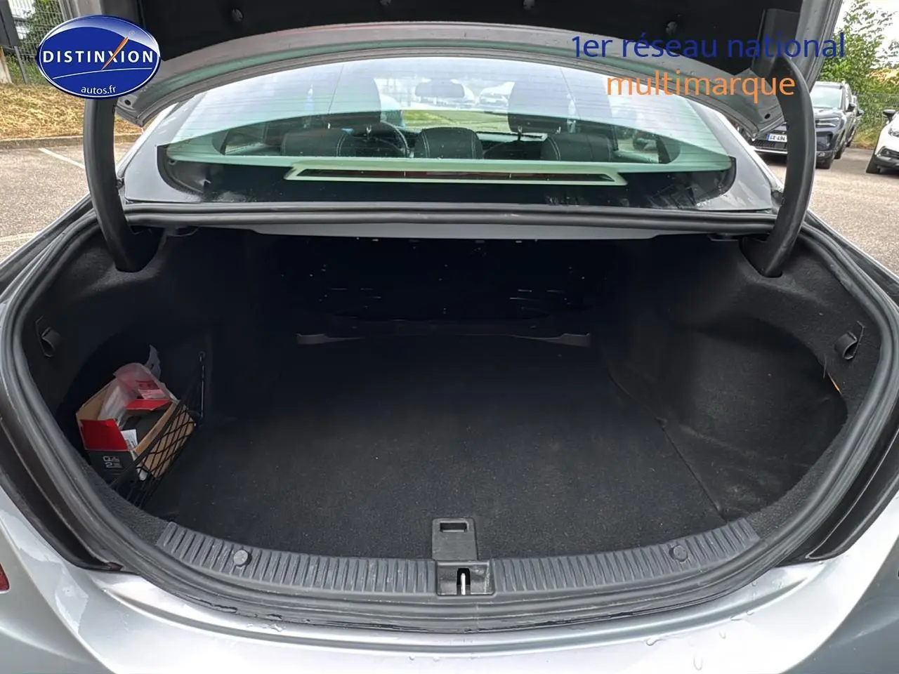 Coffre ouvert vu de l'arrière d'une Mercedes Classe C 180 d business gris alu, montrant un espace de rangement vide.