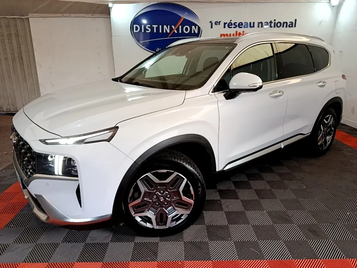 Vue 3/4 avant droit du Hyundai Santa Fe blanc avec phares LED allumés et jantes alliage distinctives.