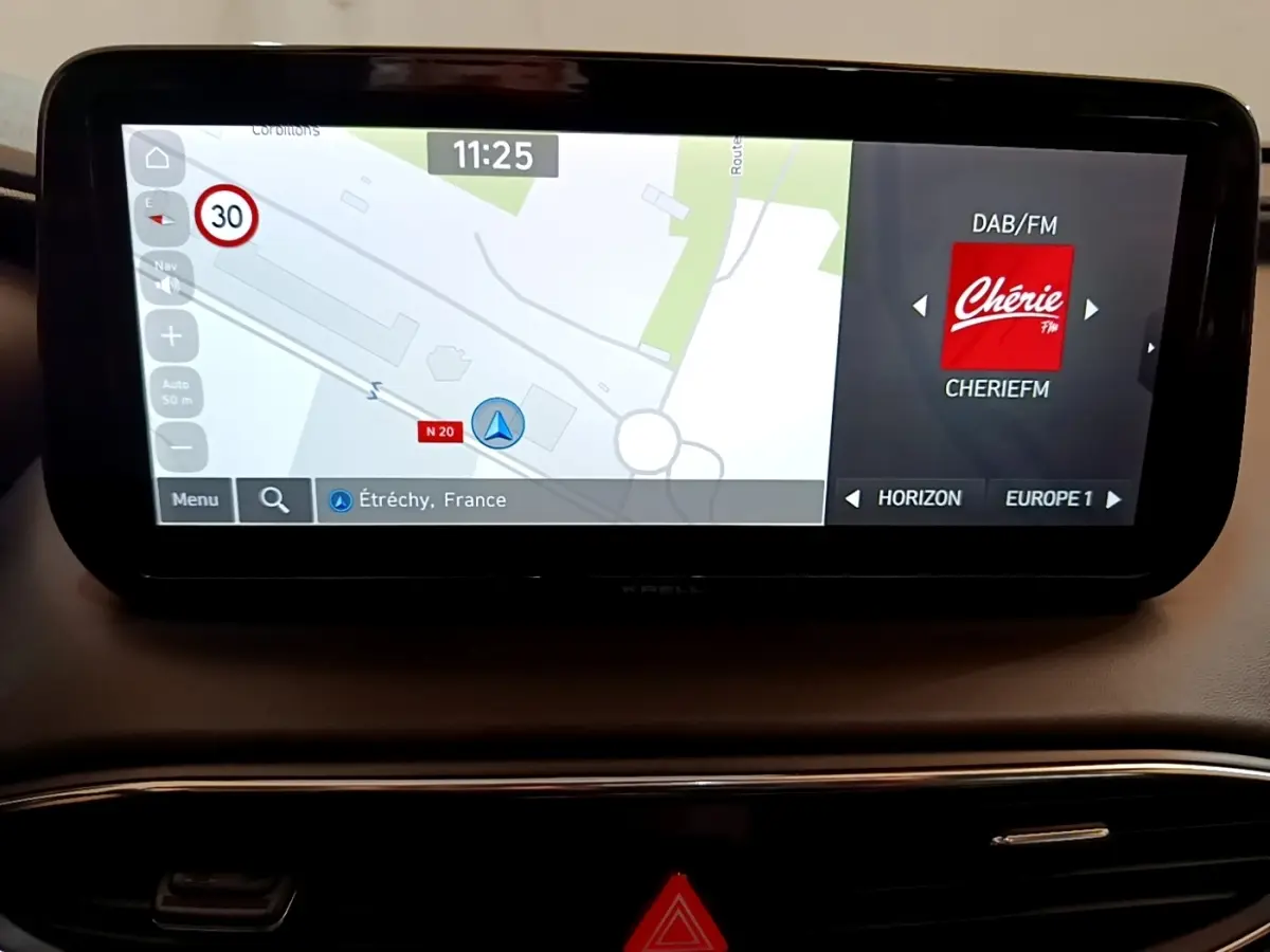 Écran tactile central du Hyundai Santa Fe hybride 2022 affichant navigation et radio Chérie FM sur tableau de bord noir.