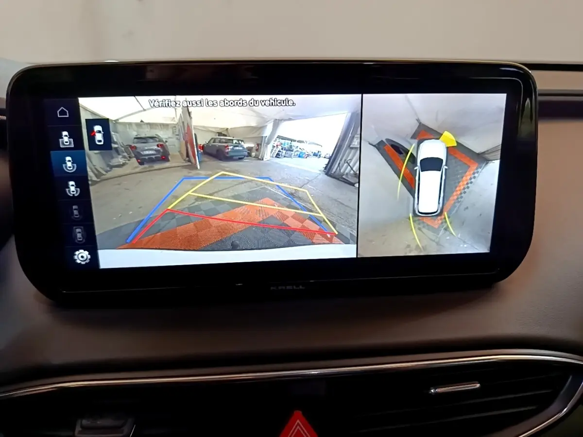 Écran tactile intérieur montrant la caméra de recul et vue à 360° du Hyundai Santa Fe blanc en stationnement.