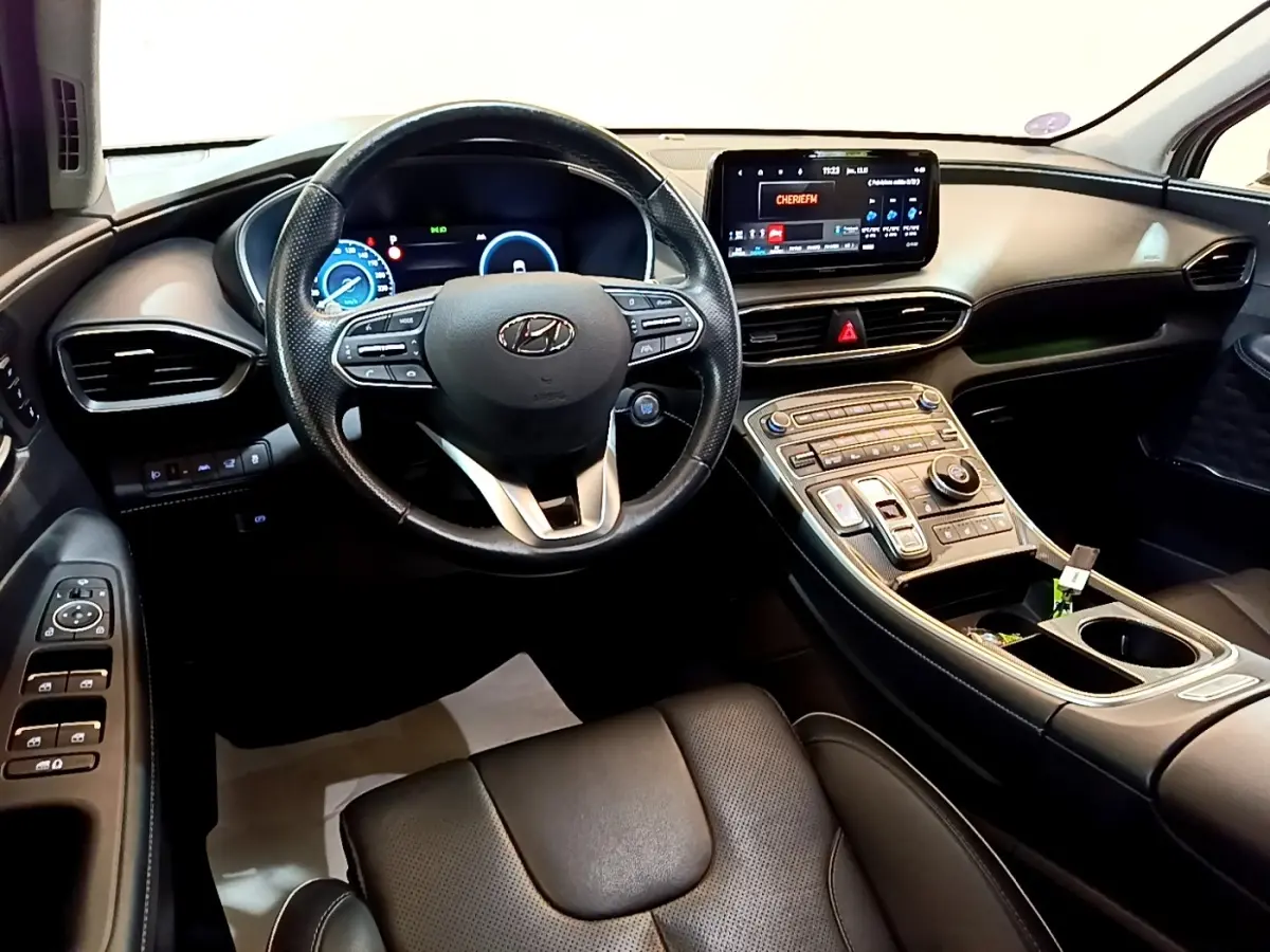 Vue intérieure du tableau de bord et volant cuir noir du Hyundai Santa Fe hybride 2022 avec écran tactile central.