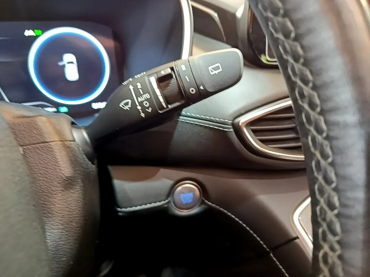 Gros plan intérieur sur la commande d'essuie-glace et bouton démarrage bleu du Hyundai Santa Fe blanc 2022, côté gauche du volant.