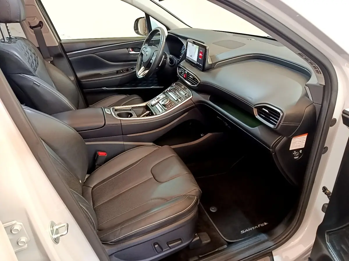 Intérieur côté conducteur du Hyundai Santa Fe blanc 2022, sièges cuir noirs et tableau de bord avec écran tactile.
