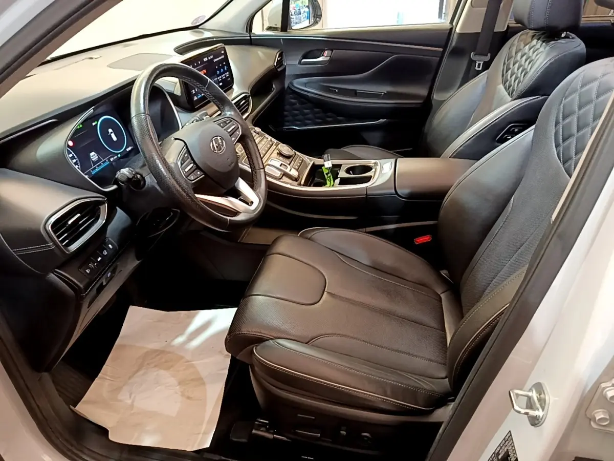 Intérieur avant droit du Hyundai Santa Fe blanc 2022, sièges cuir noirs avec surpiqûres et tableau de bord digital.