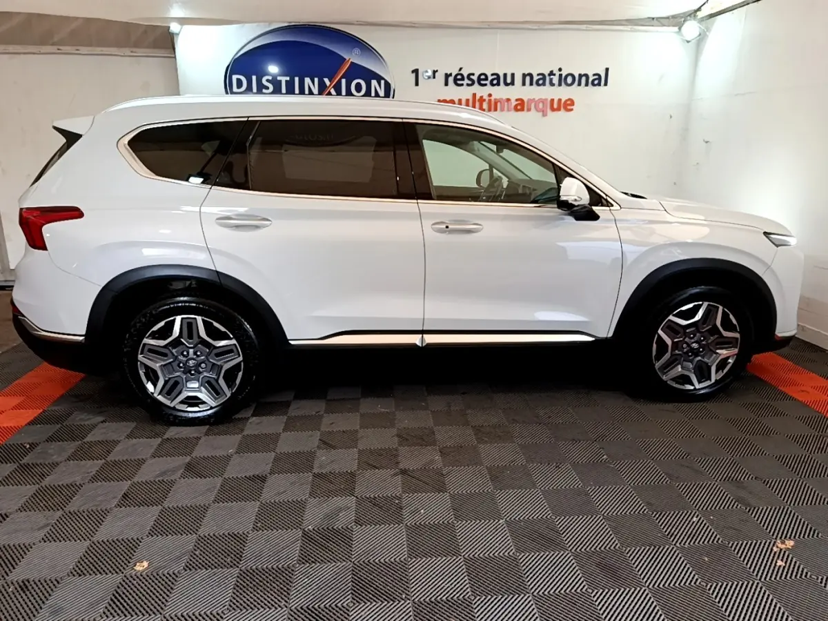 Vue de profil côté gauche d'un Hyundai Santa Fe blanc 7 places avec jantes alliage et vitres teintées.