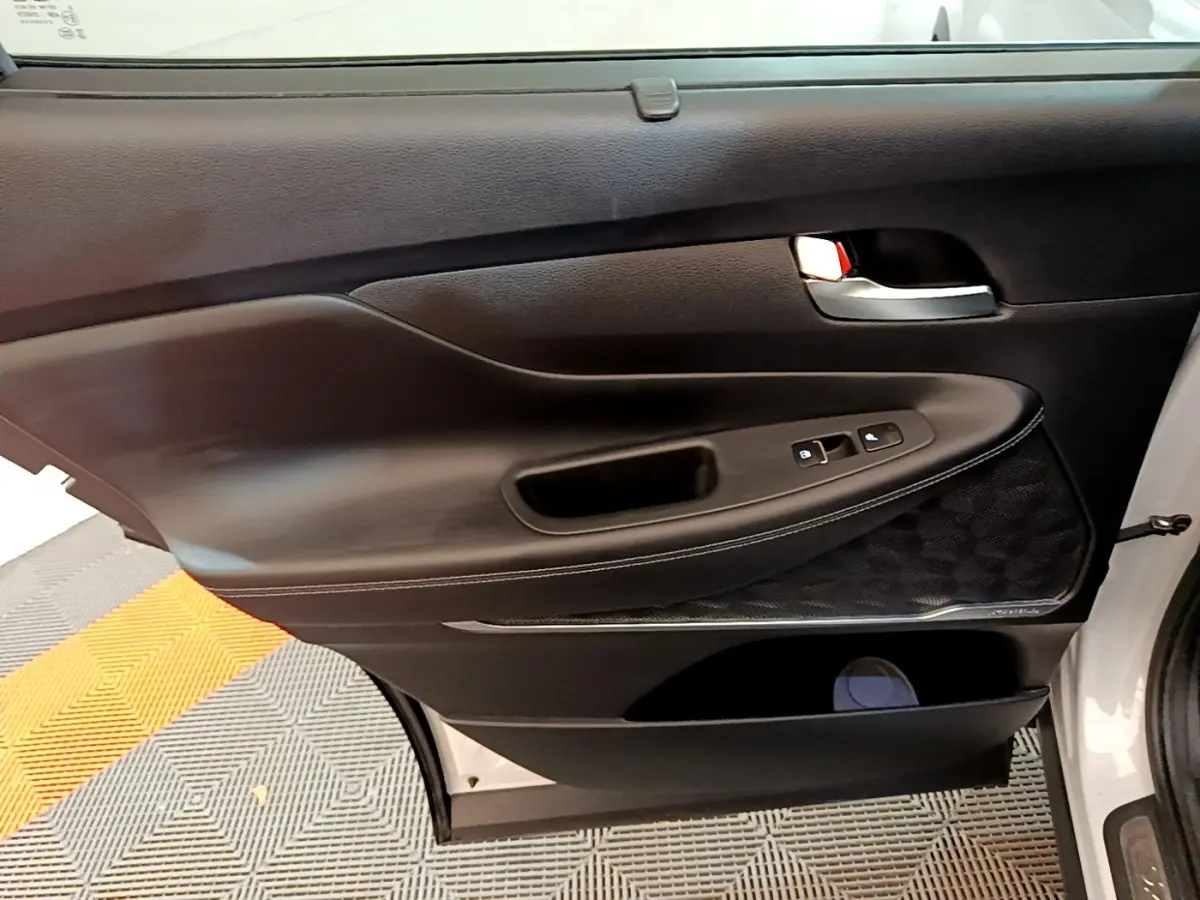 Gros plan sur la porte intérieure côté droit du Hyundai Santa Fe blanc, avec commandes de vitres et poignée argentée.