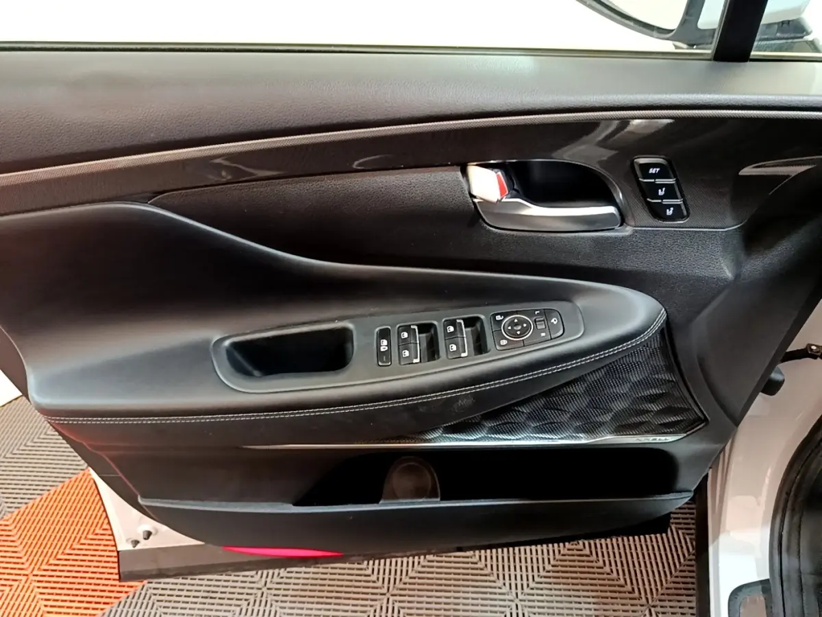 Panneau de porte côté conducteur noir avec commandes électriques et insert décoratif sur Hyundai Santa Fe blanc 2022.