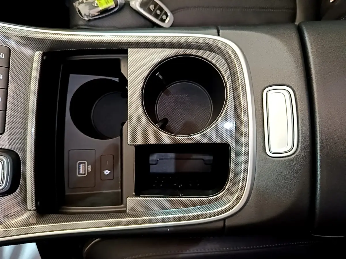 Gros plan sur la console centrale du Hyundai Santa Fe blanc 2022, avec porte-gobelets et prise USB visible.