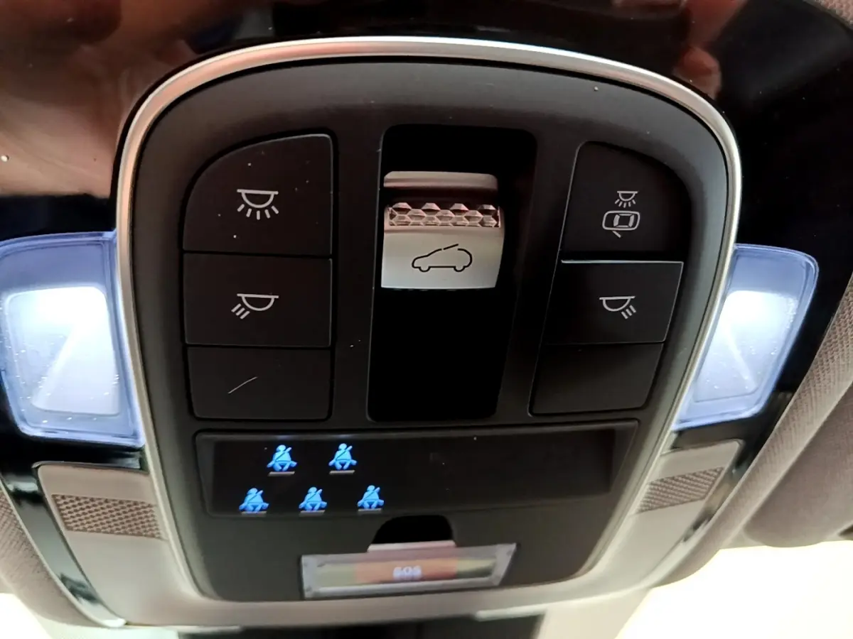 Vue en gros plan du panneau de commandes plafonnier intérieur du Hyundai Santa Fe blanc, avec éclairages et icônes de sécurité bleues.