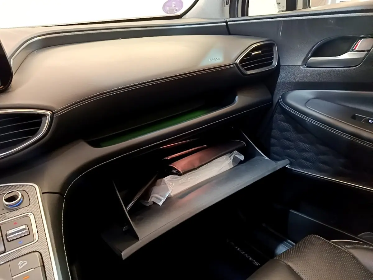 Intérieur côté passager du Hyundai Santa Fe 2022, boîte à gants ouverte avec documents visibles, sellerie noire.