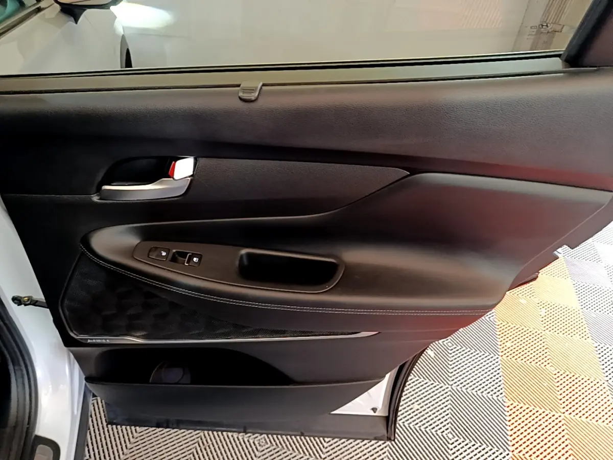 Gros plan sur la porte arrière gauche blanche du Hyundai Santa Fe 2022 avec garniture noire et commandes de fenêtre.