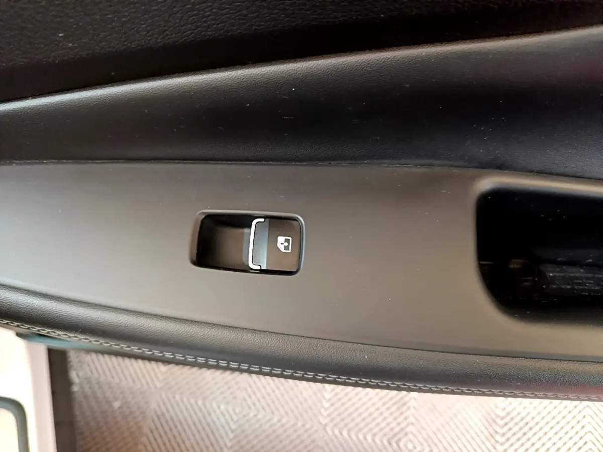 Gros plan sur le bouton de verrouillage des portes intégré dans la garniture noire de la portière intérieure du Hyundai Santa Fe blanc.