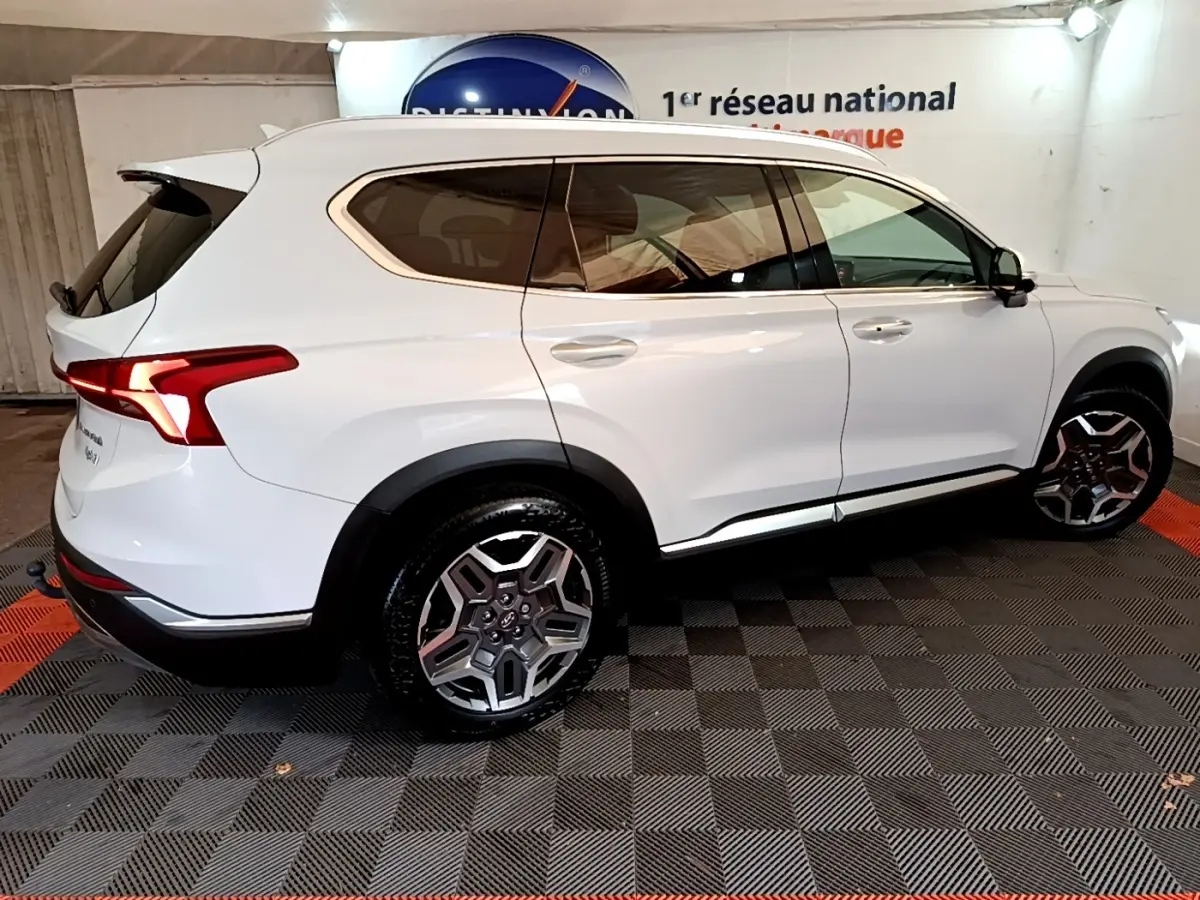 Vue latérale droite du Hyundai Santa Fe blanc 2022, soulignant ses jantes alliage et ses vitres teintées.