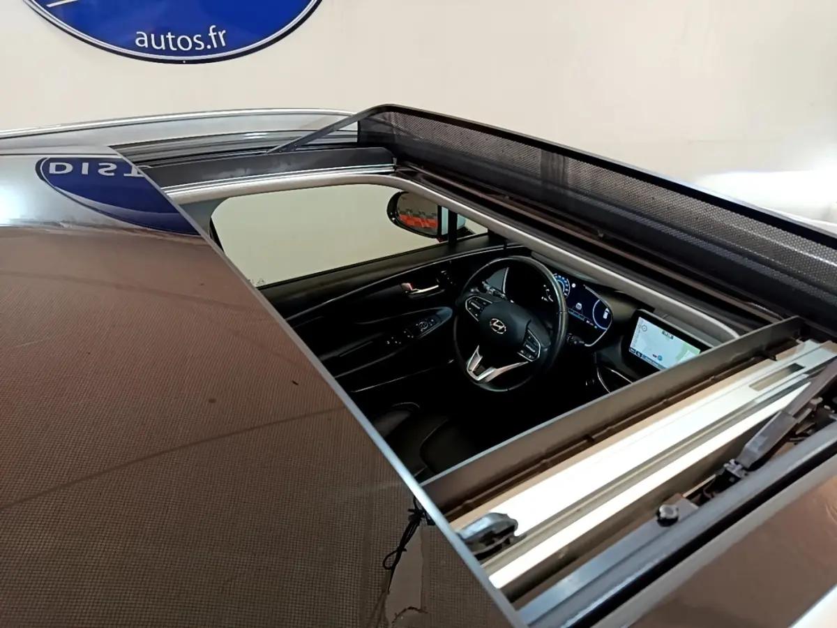 Vue plongeante sur l'intérieur noir du Hyundai Santa Fe 2022 via toit ouvrant panoramique ouvert.