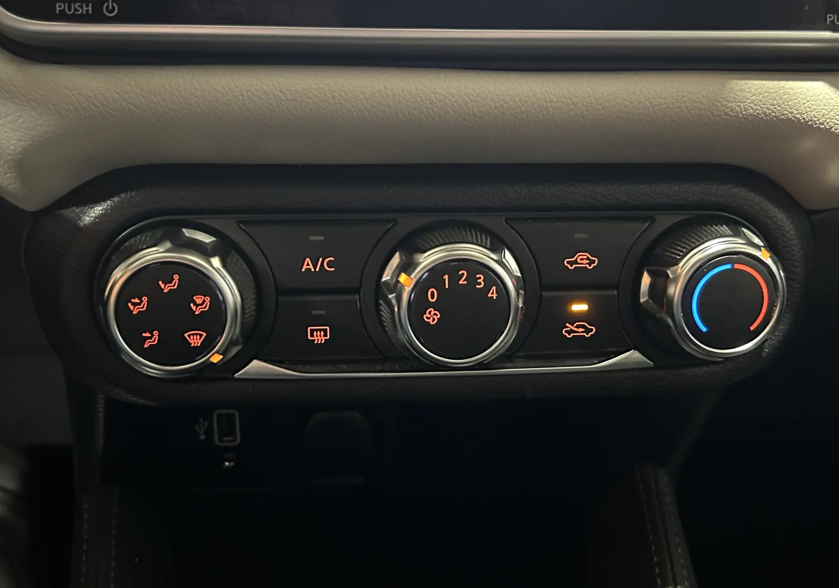 Gros plan sur les commandes de climatisation avec réglages rotatifs et voyants allumés dans une Nissan Micra blanche de 2021.