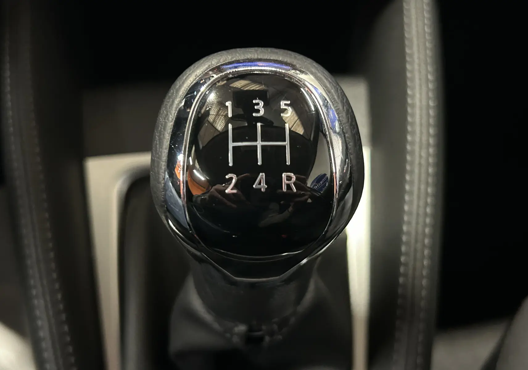 Gros plan sur le levier de vitesses manuel noir et chrome de la Nissan Micra blanche de 2021, intérieur sombre.