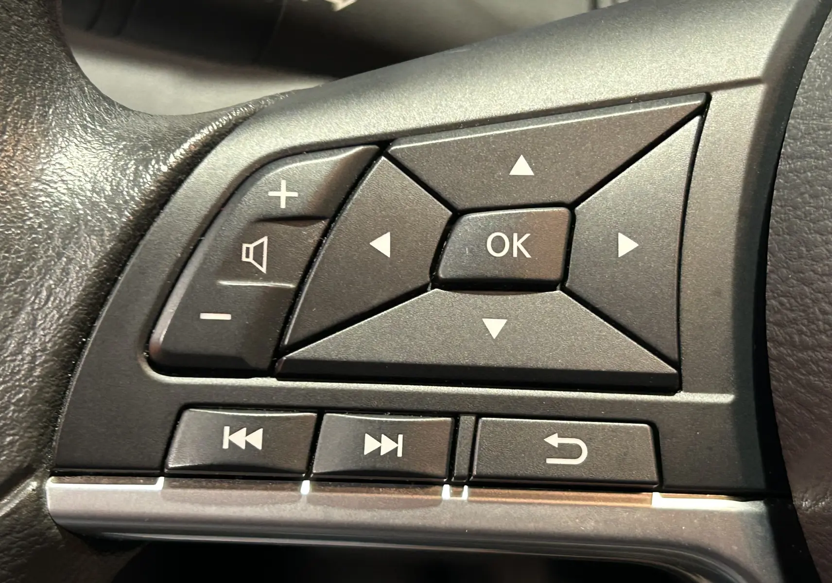 Gros plan sur les commandes multifonctions noires à droite du volant de la Nissan Micra blanche de 2021.