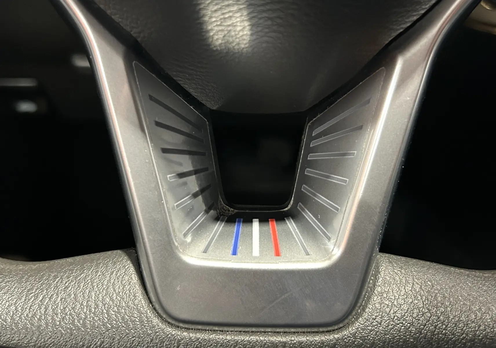 Détail du volant de la Nissan Micra 2021 avec insert tricolore bleu, blanc, rouge au centre.