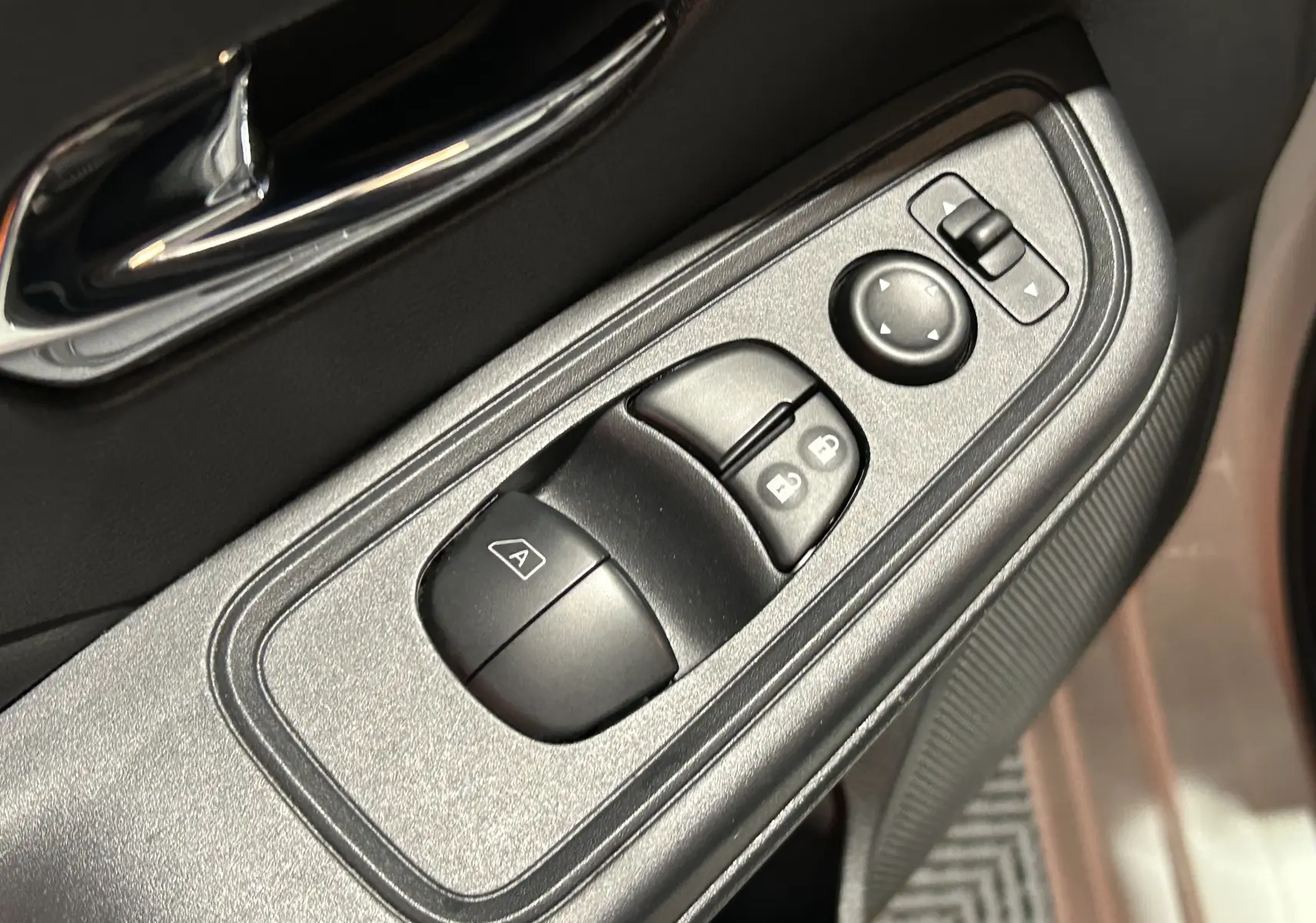 Gros plan sur les commandes de lève-vitres et rétroviseurs côté conducteur d'une Nissan Micra blanche 2021.