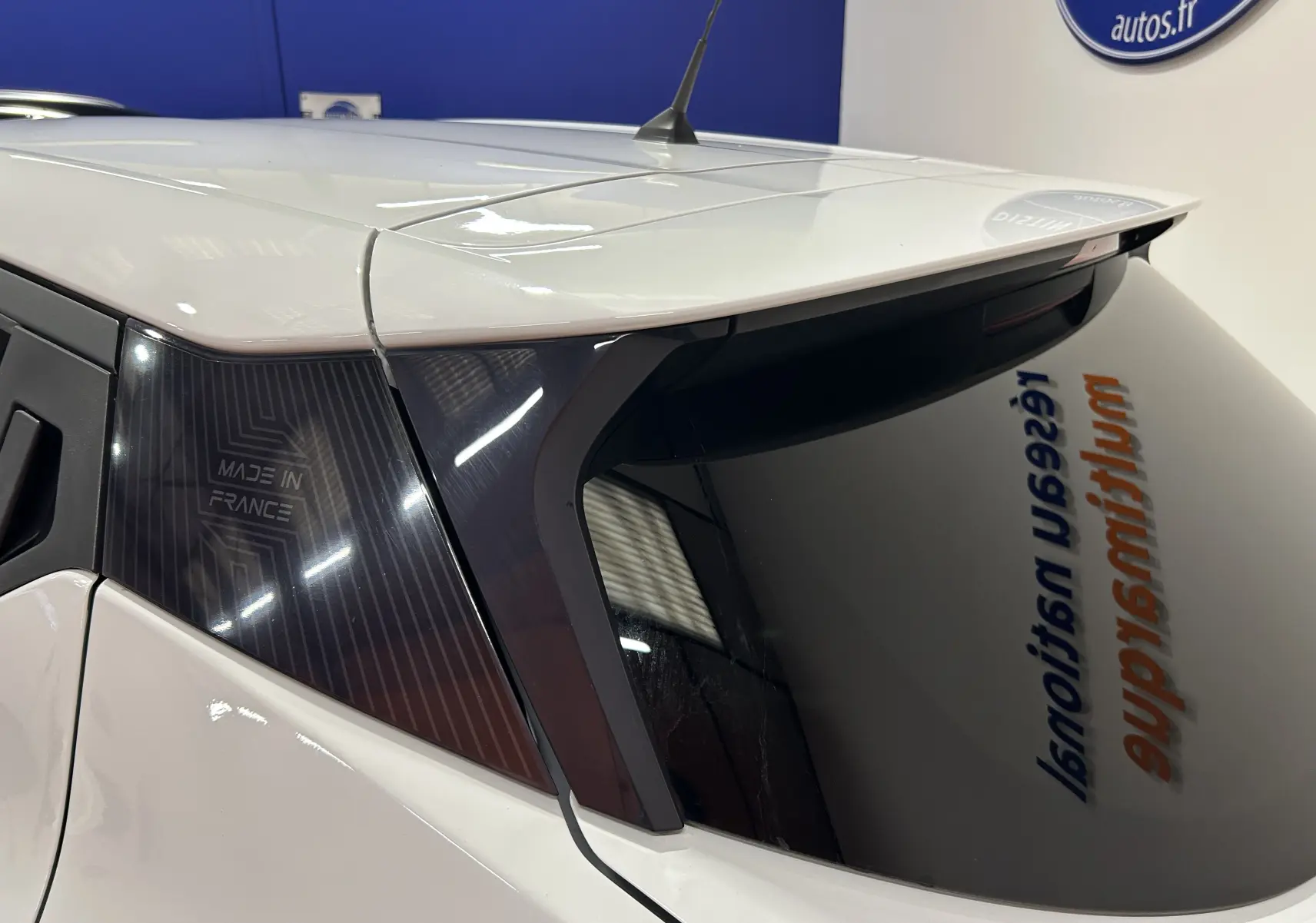 Vue arrière côté gauche d'une Nissan Micra blanche avec vitrage teinté et inscription "Made in France" sur la custode.