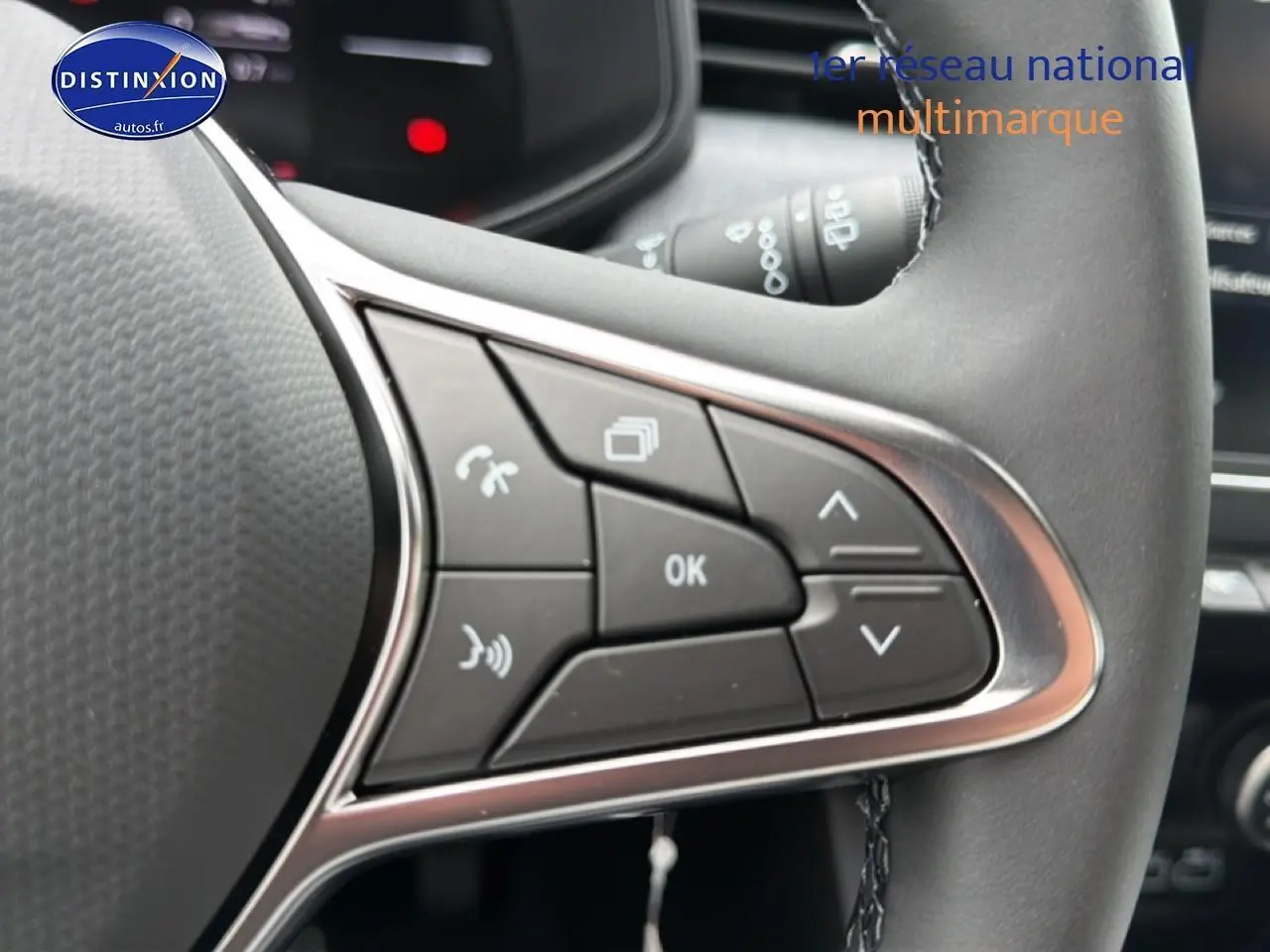 Gros plan sur les commandes multifonctions à droite du volant de la Renault Clio V gris schiste, avec boutons de gestion d'appels et menu.