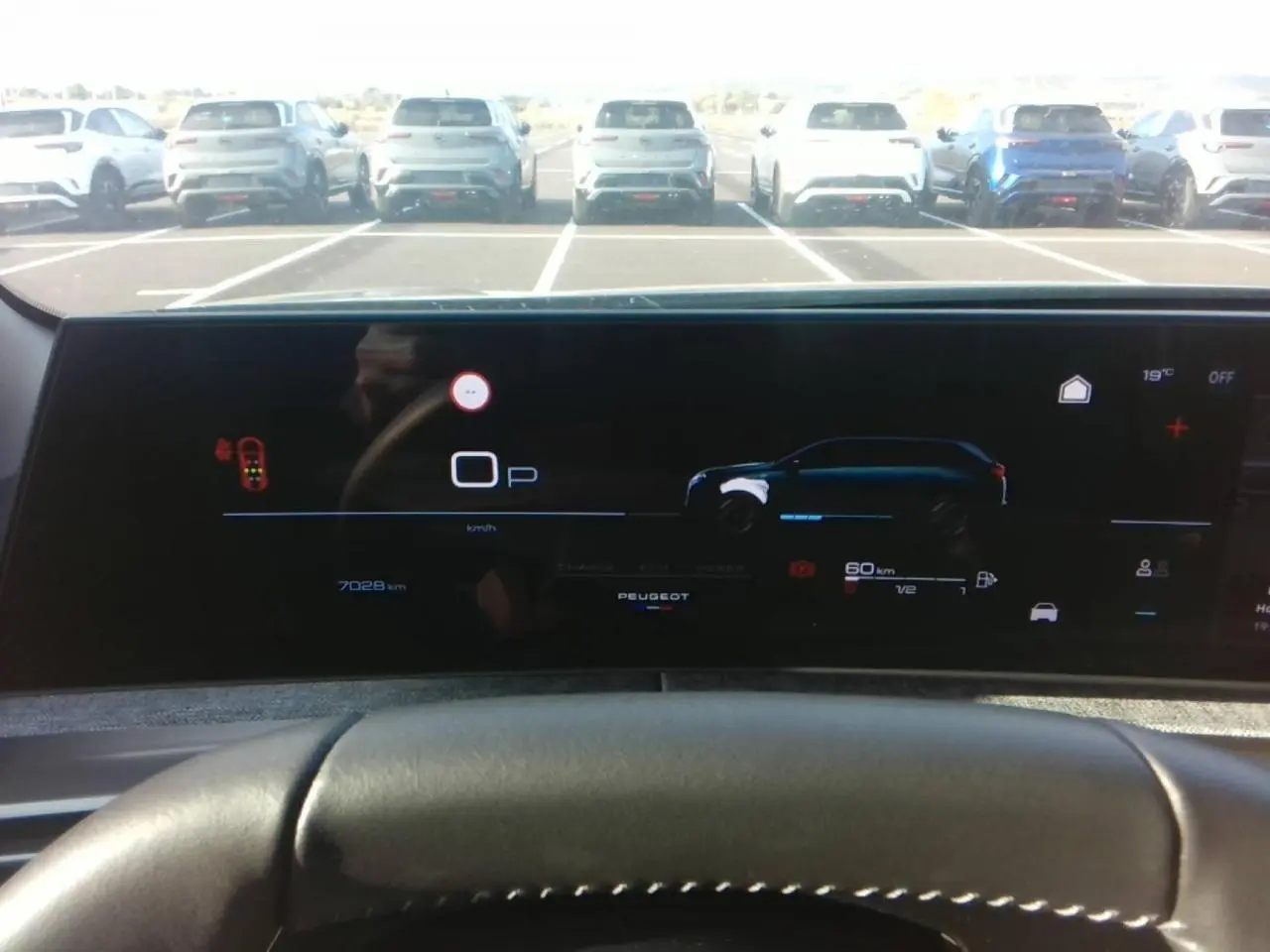 Vue intérieure du tableau de bord numérique du Peugeot 5008 hybride, affichant l'autonomie et la vitesse, avec volant en premier plan.