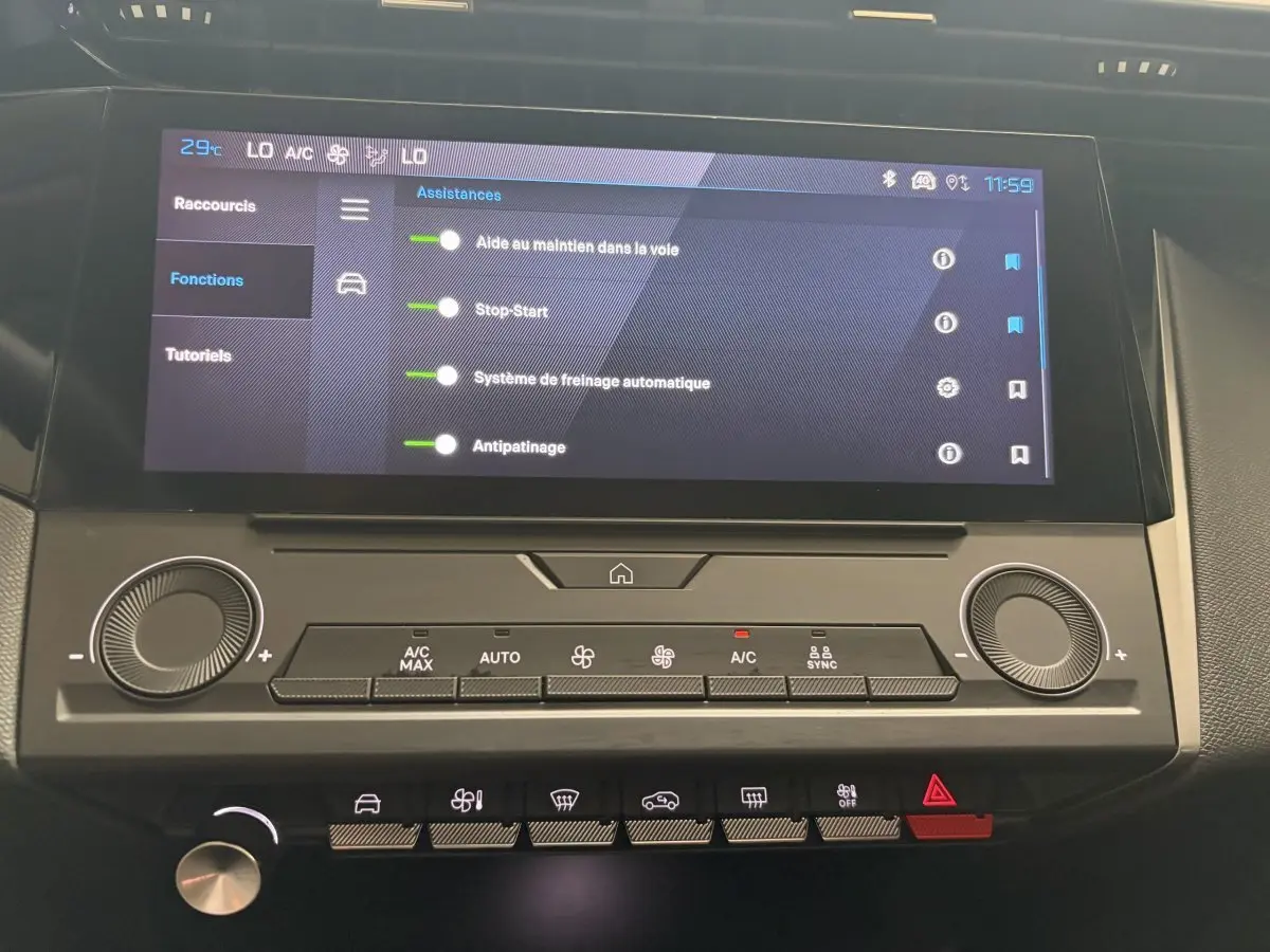 Gros plan sur l'écran tactile central et les commandes de climatisation de la Peugeot 308 blanche de 2024.