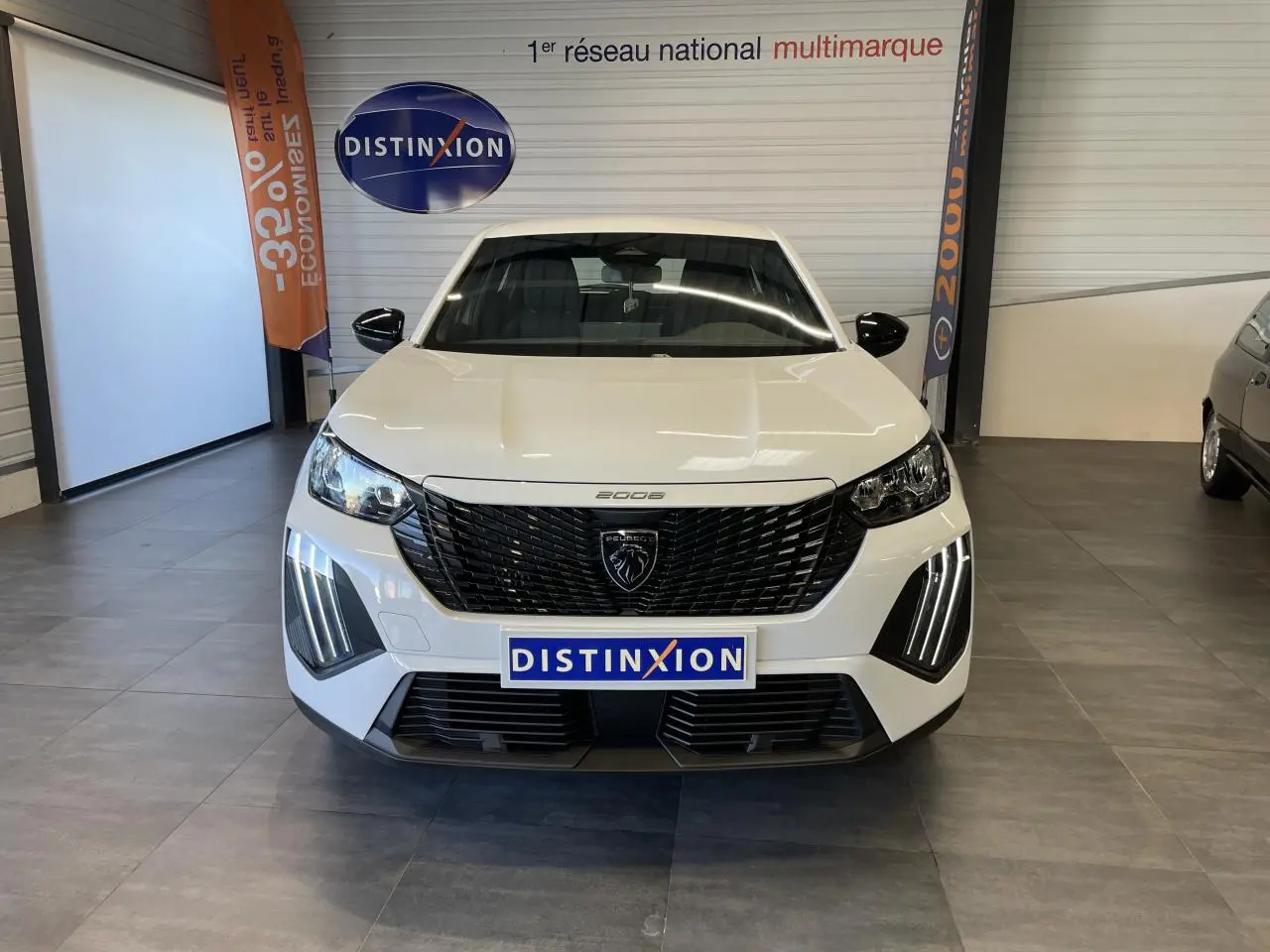 Vue avant d'un Peugeot 2008 blanc avec calandre noire et feux diurnes LED en griffes, en showroom intérieur.