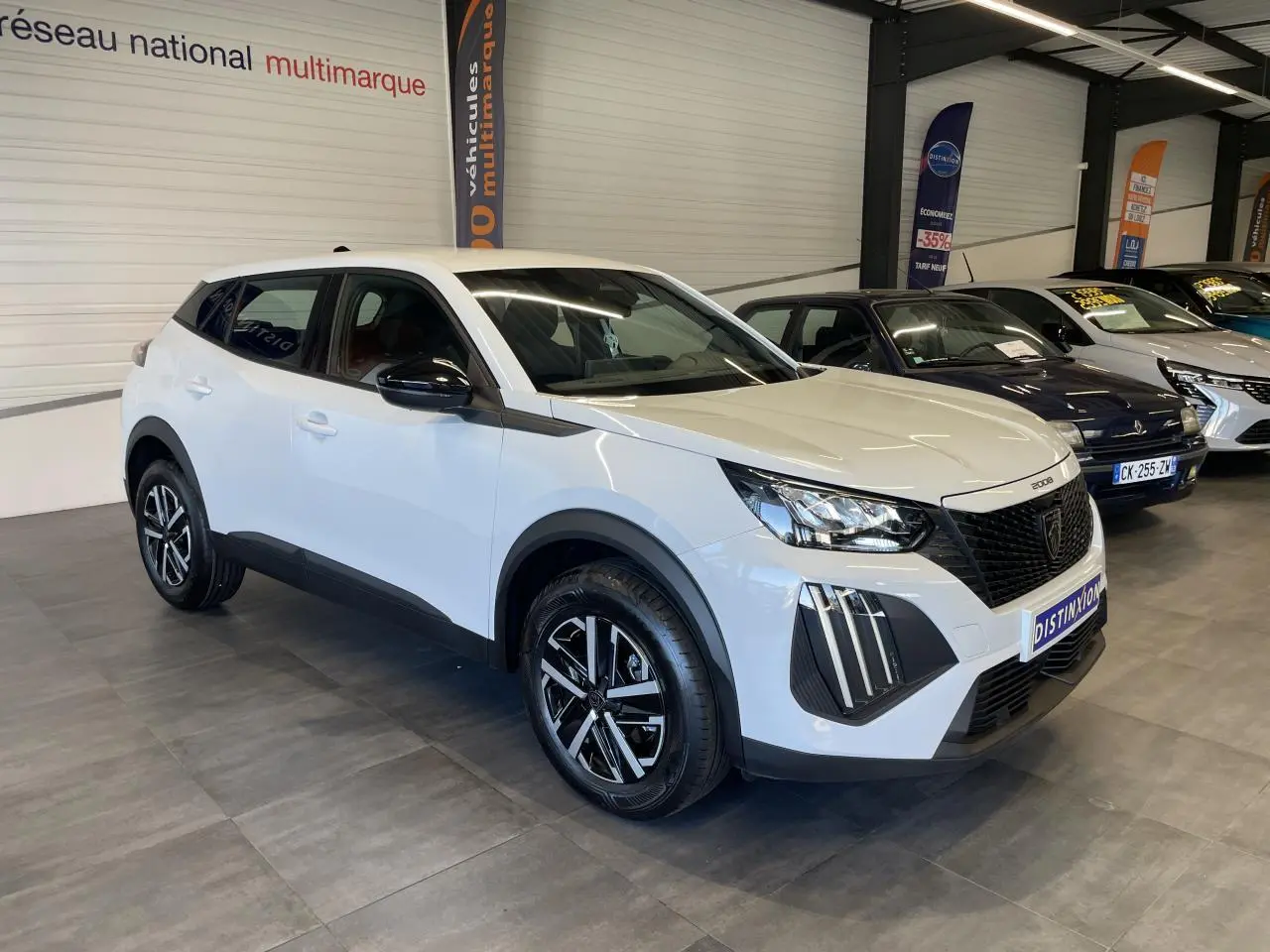 Peugeot 2008 blanc en 3/4 avant droit, avec calandre noire et jantes alliage bicolores en showroom.