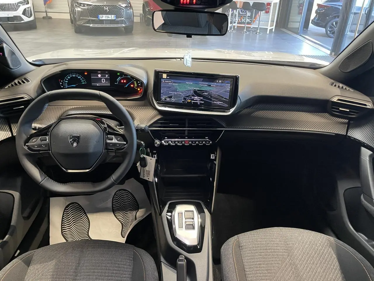 Vue intérieure avant du Peugeot 2008 blanc, avec tableau de bord numérique, écran tactile central et volant compact cuir.