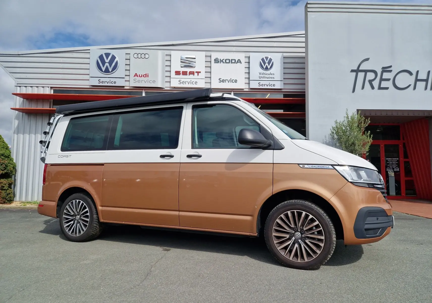Vue latérale droite d'un Volkswagen California 2.0 TDi Cooper bronze avec toit relevable et jantes alliage.