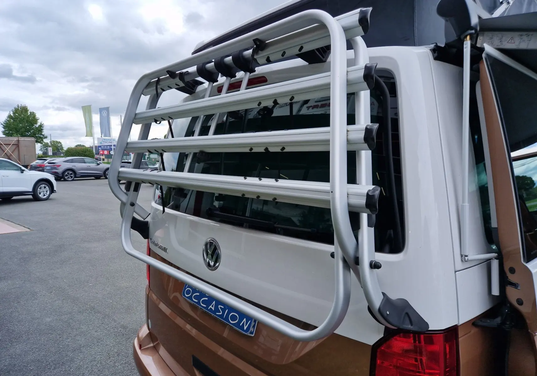 Vue arrière du Volkswagen California Cooper bronze 2021 avec porte-vélos fixé sur le hayon blanc.