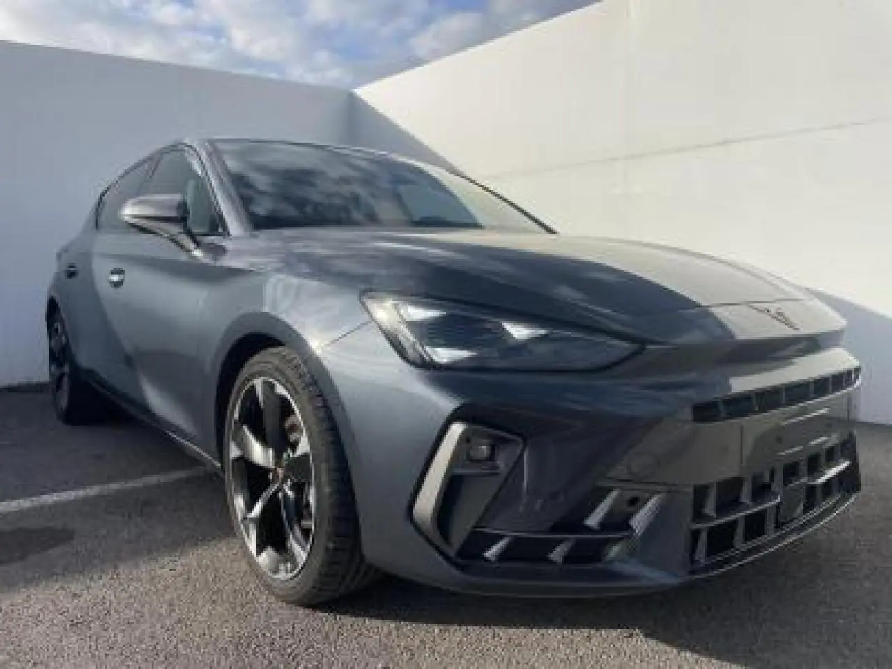 Vue 3/4 avant gauche d'une CUPRA Leon 2025 gris magnetic metal avec jantes alliage noires et phares Full LED Tri-LED.