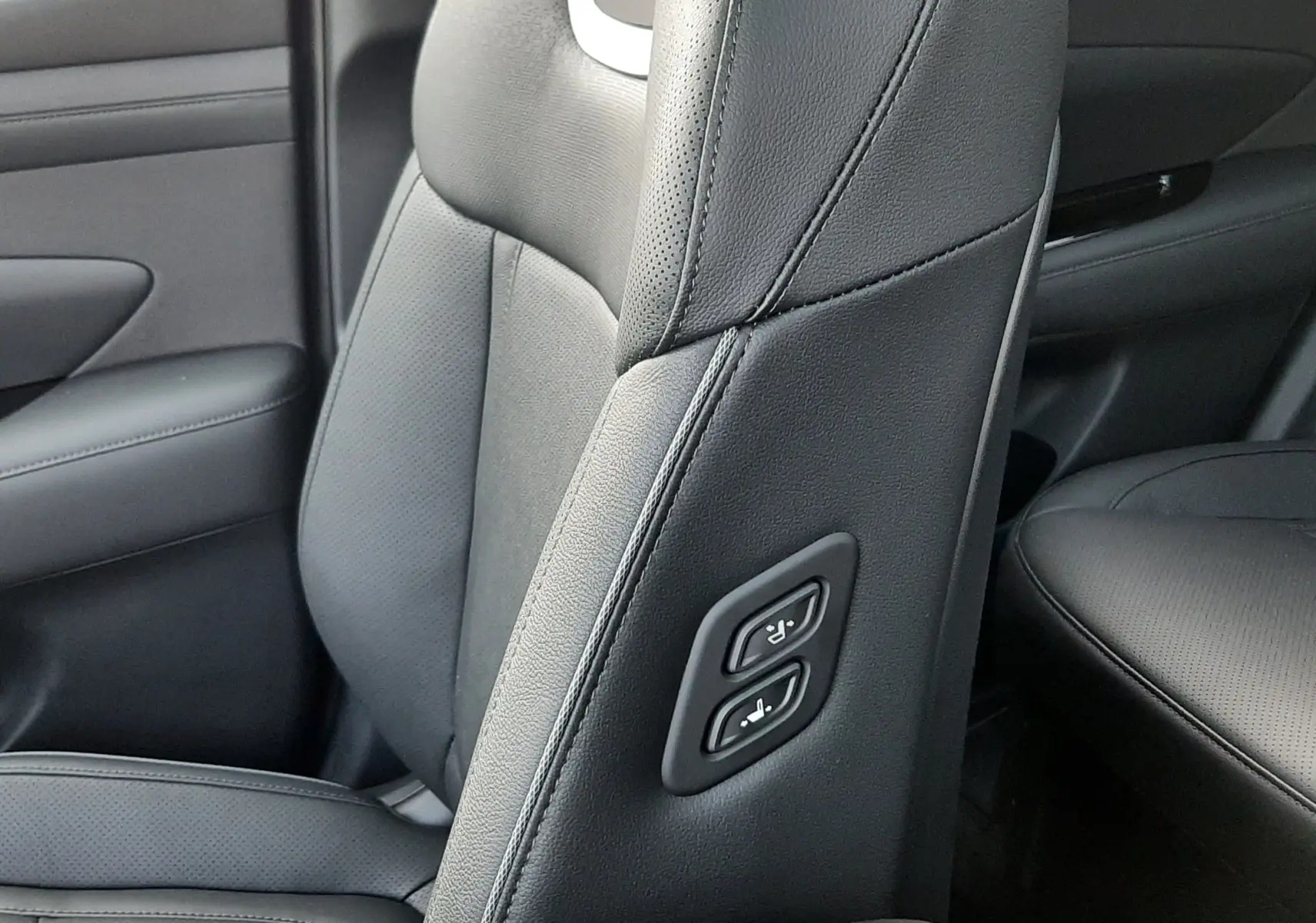 Détail du siège avant gauche en cuir noir du Hyundai Tucson 2025 avec commandes électriques intégrées sur la tranche.