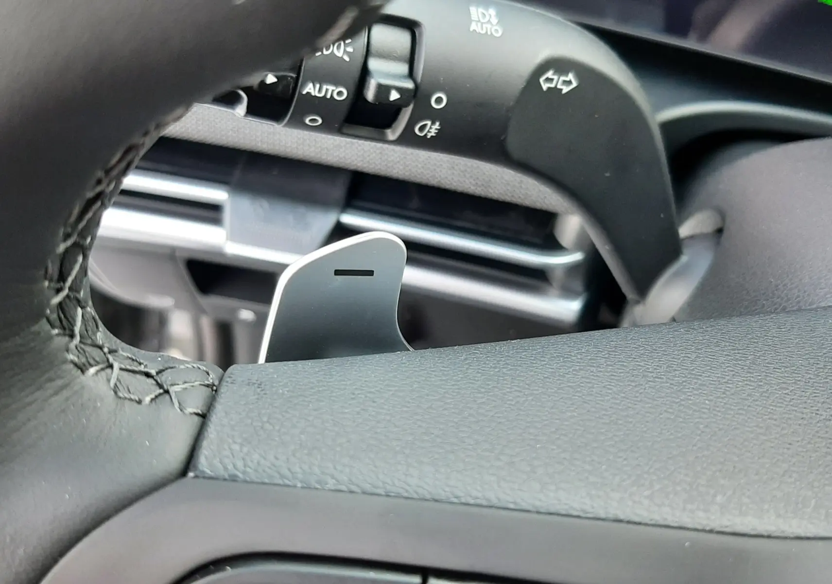 Gros plan sur le volant noir et la commande des clignotants du Hyundai Tucson 2025 hybride, intérieur cuir.