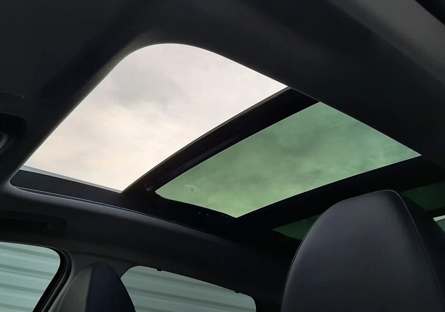 Toit panoramique ouvrant vu de l'intérieur d'un Hyundai Tucson 2025, sièges en cuir noir visibles.