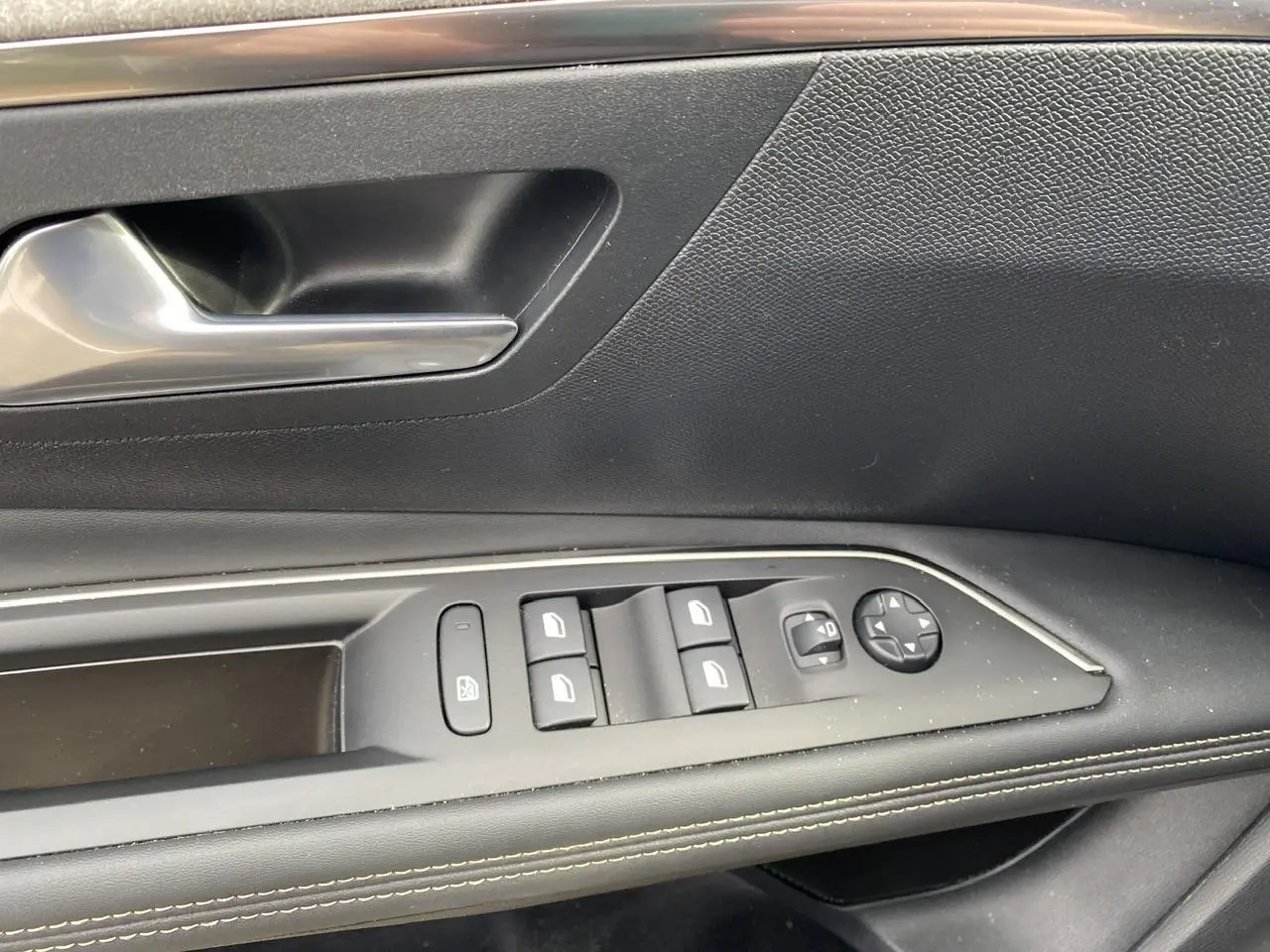 Gros plan sur la commande de lève-vitres et rétroviseurs côté conducteur du Peugeot 3008 gris foncé 2023.