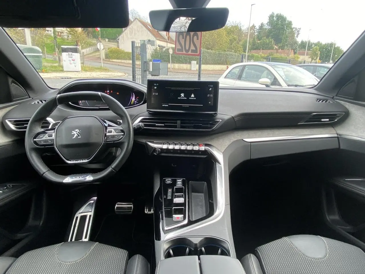 Intérieur du Peugeot 3008 2023 hybride, vue avant du poste de conduite avec écran tactile et volant compact.