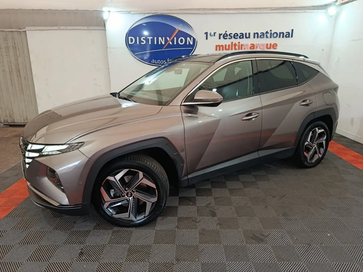 Vue 3/4 avant droite d'un Hyundai Tucson marron 2022 hybride rechargeable dans un showroom intérieur.