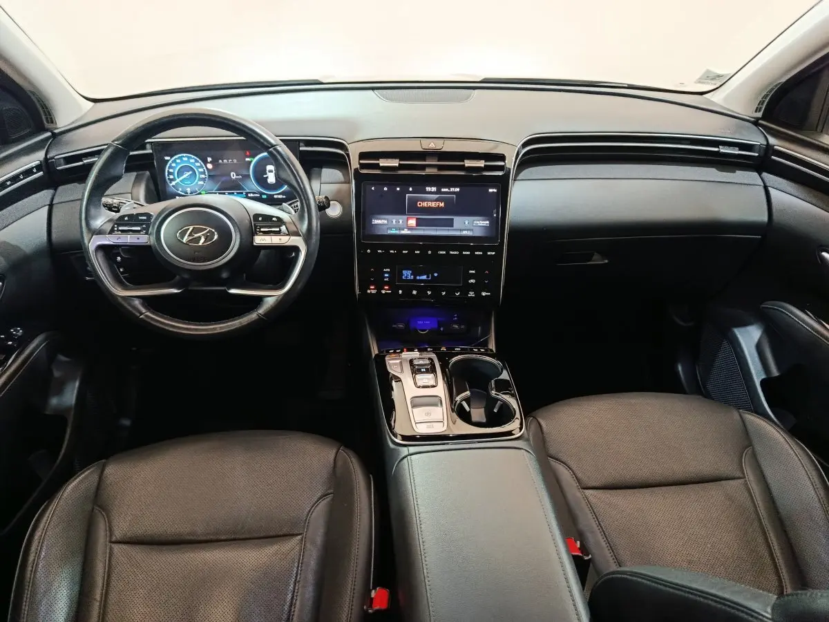 Intérieur noir du Hyundai Tucson 2022, vue frontale sur tableau de bord avec écran tactile et volant multifonctions.