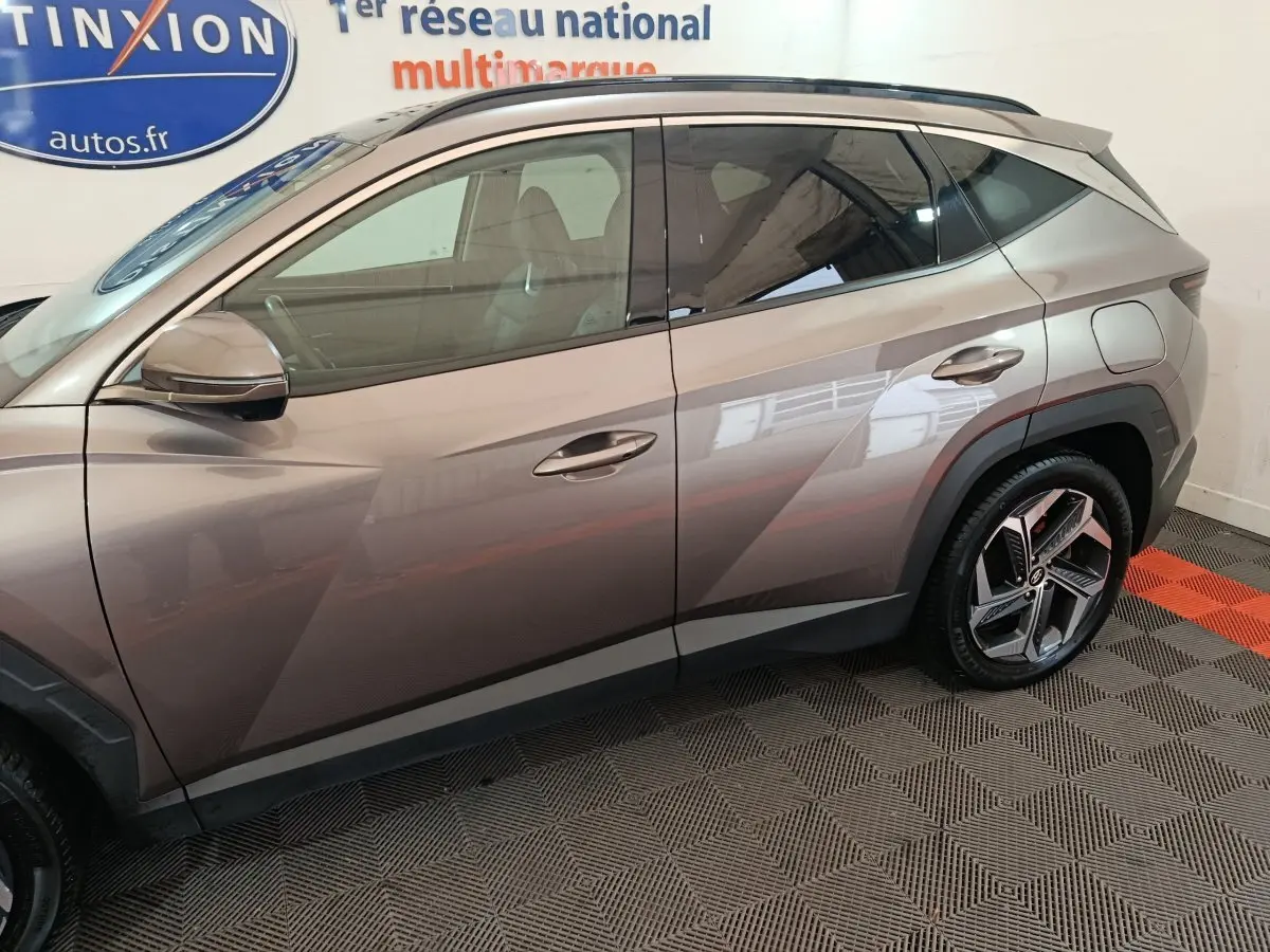 Profil côté gauche d'un Hyundai Tucson marron 2022 avec jantes alliage et lignes anguleuses marquées.