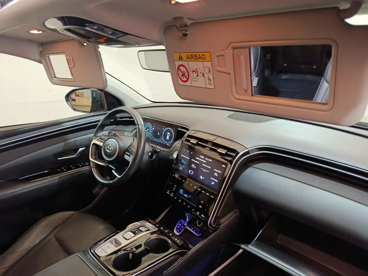 Intérieur du Hyundai Tucson 2022 vu côté conducteur, tableau de bord noir avec écran tactile et volant cuir.