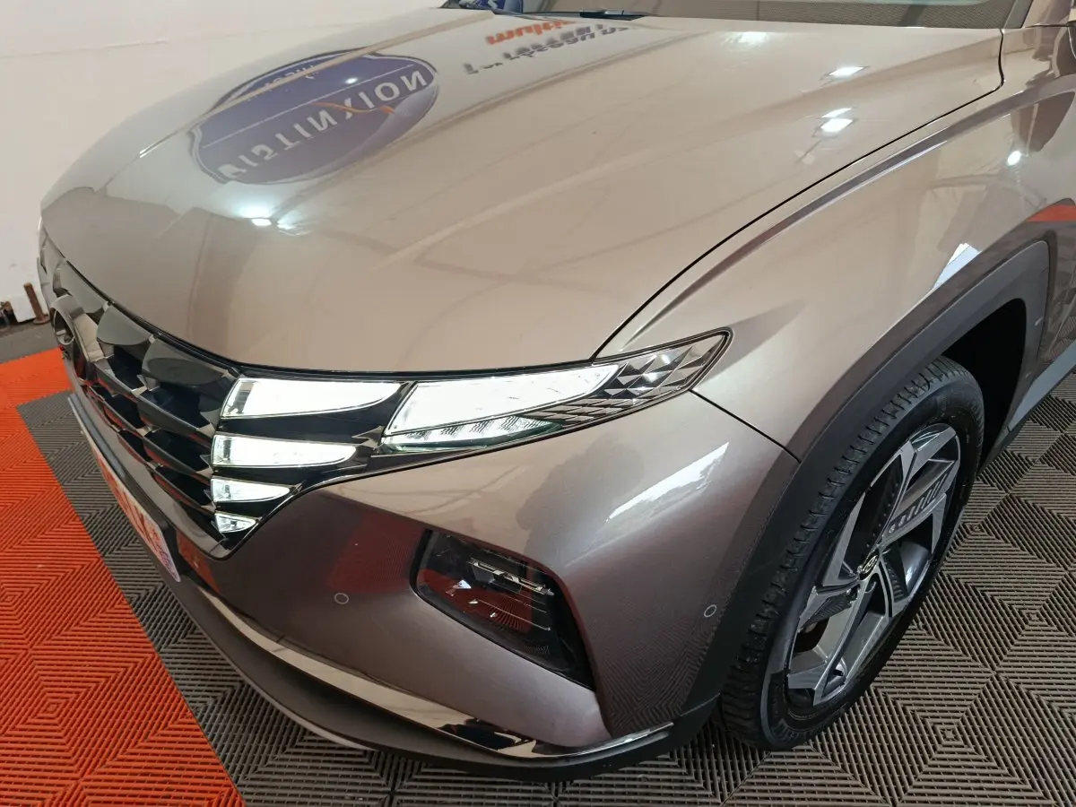 Vue 3/4 avant droit du Hyundai Tucson marron 2022 avec phares LED et jante alliage distinctive.