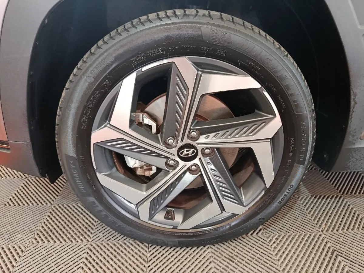 Gros plan sur la roue avant droite du Hyundai Tucson marron 2022 avec jante alliage au design géométrique.
